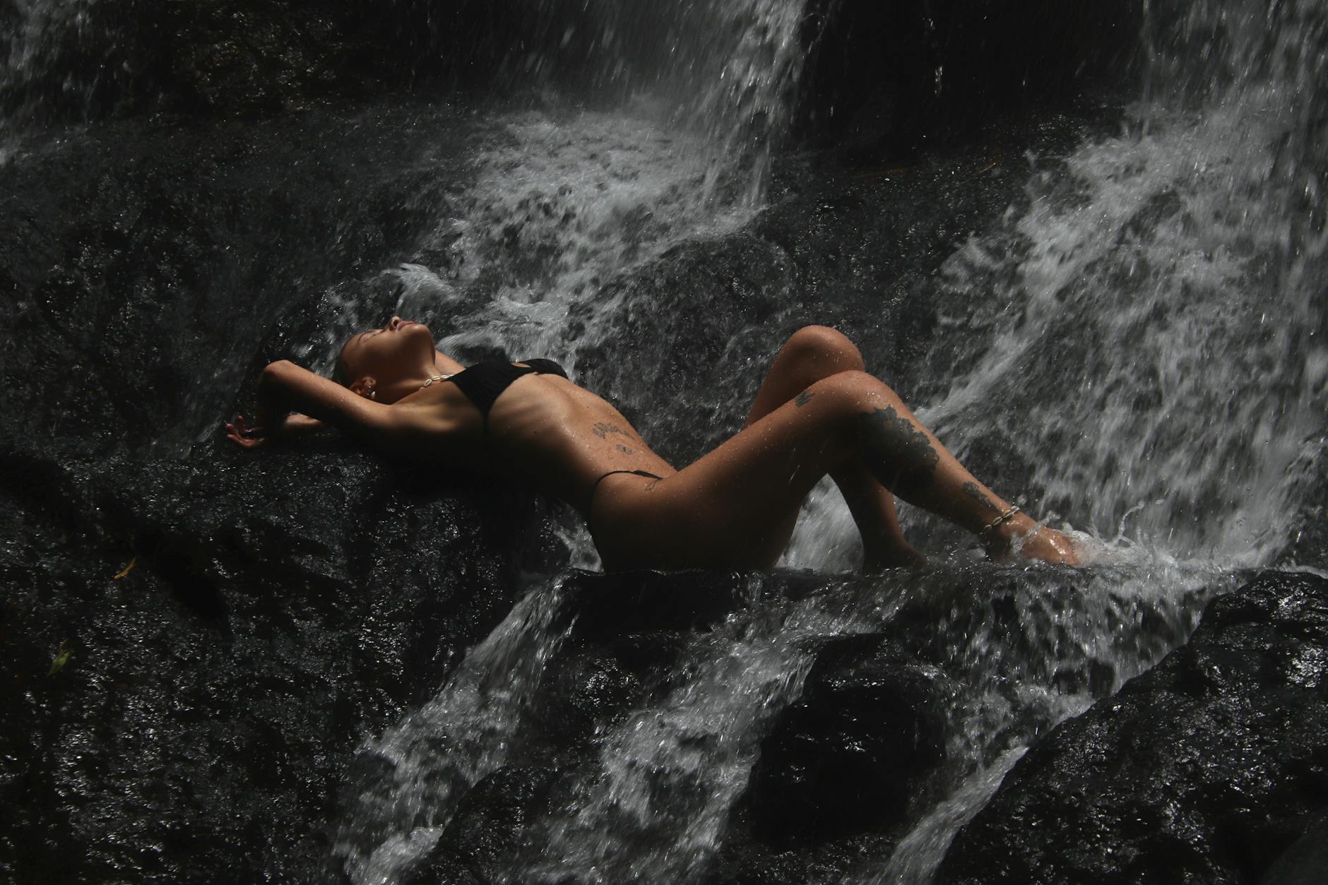 a woman posing by a waterfall